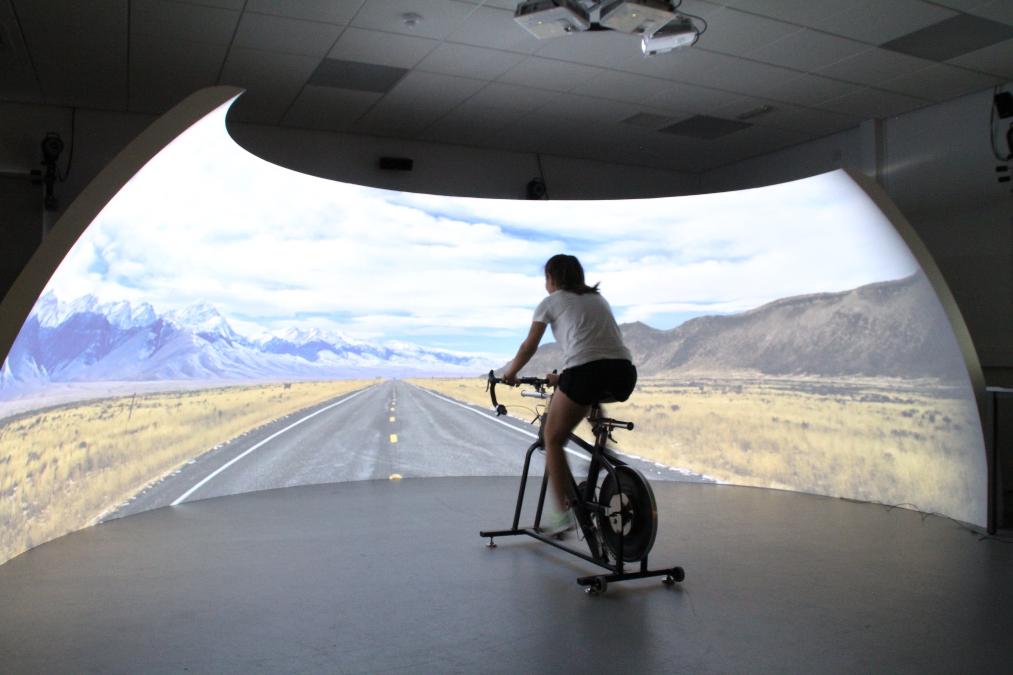 Woman riding bike in front of igloo projected road.