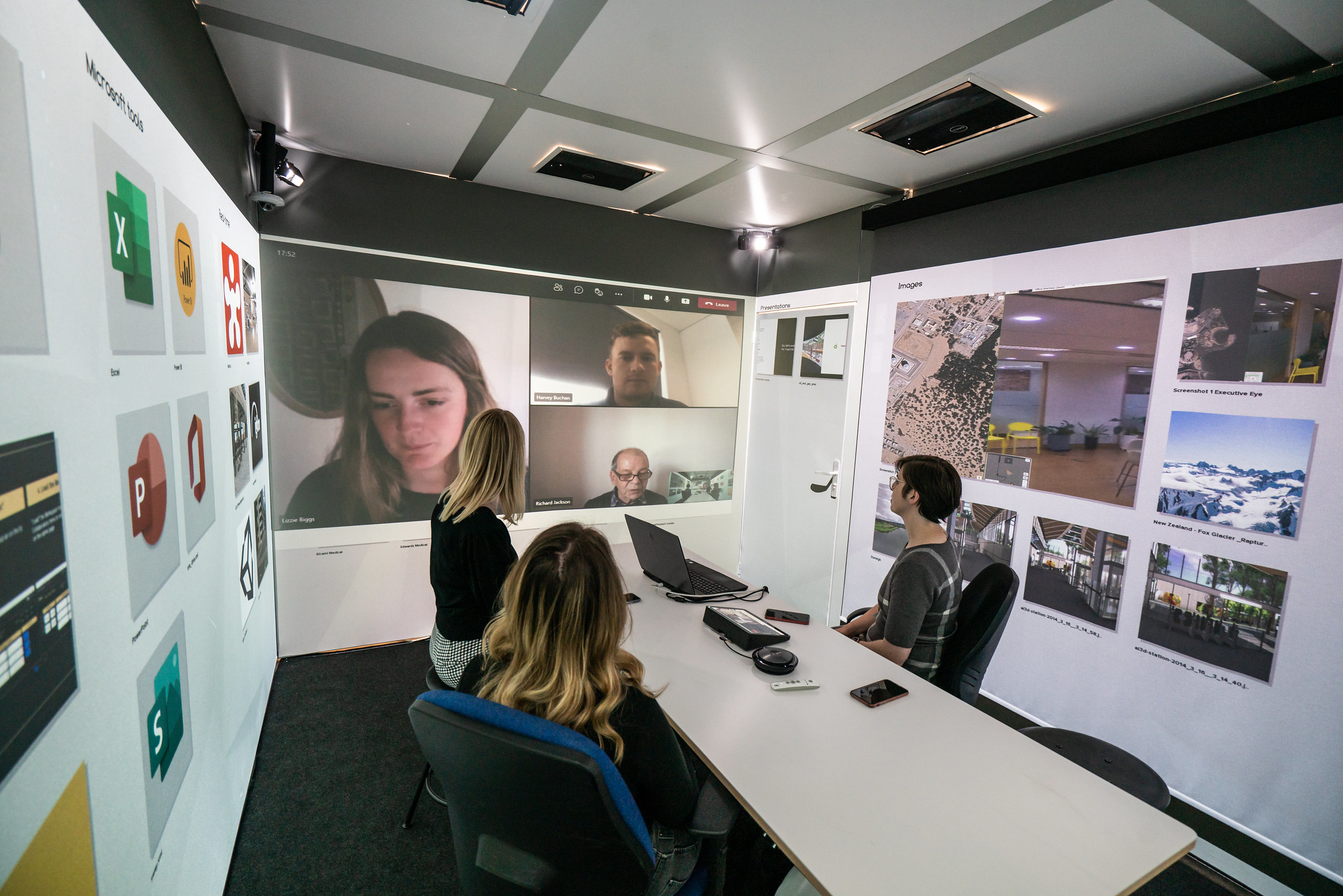 Three people in an immersive workspace, using the screens for Zoom.