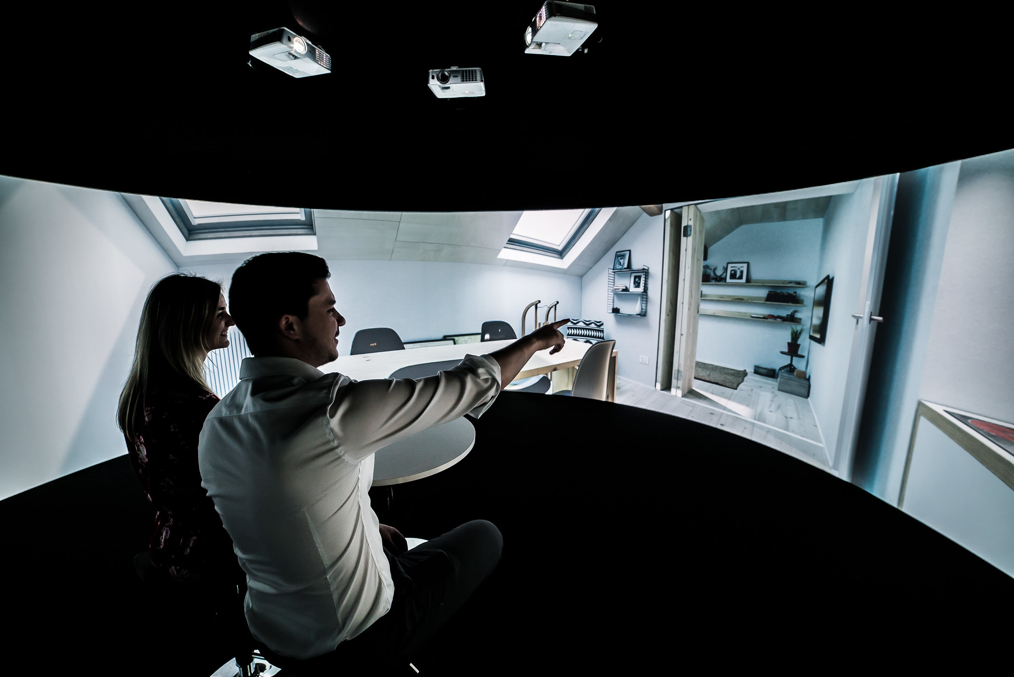 Two people pointing at a projection of a bedroom on Igloo technology.