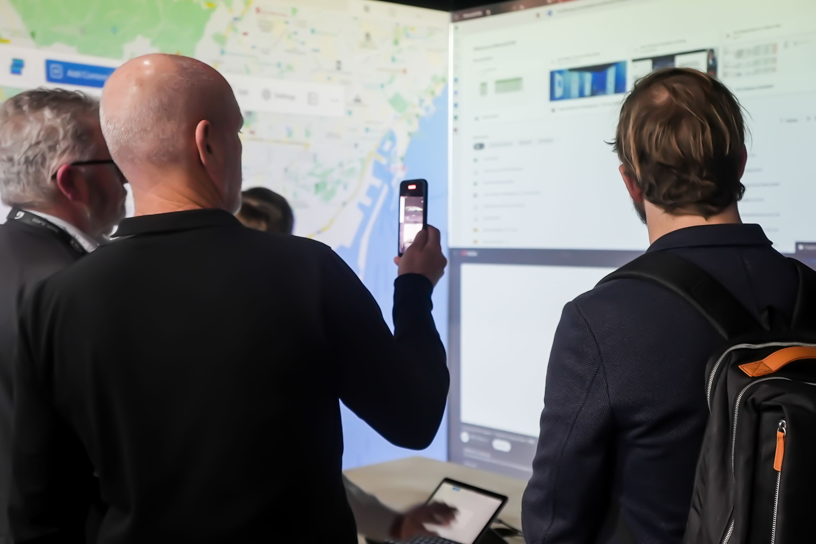 people at the event recording the set up with maps on the screen